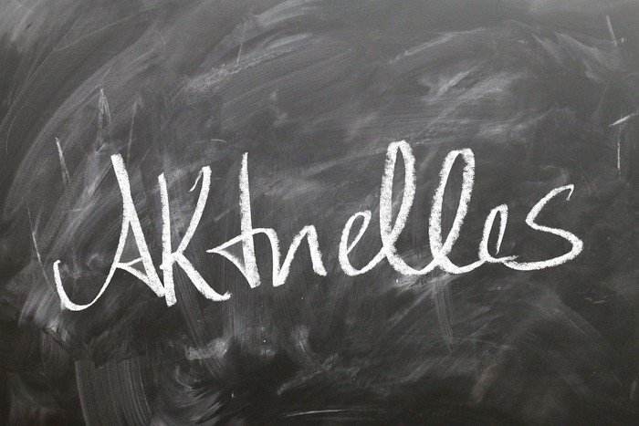 Schiefertafel, auf die mit weißer Kreide das Wort "Aktuelles" geschrieben wurde.