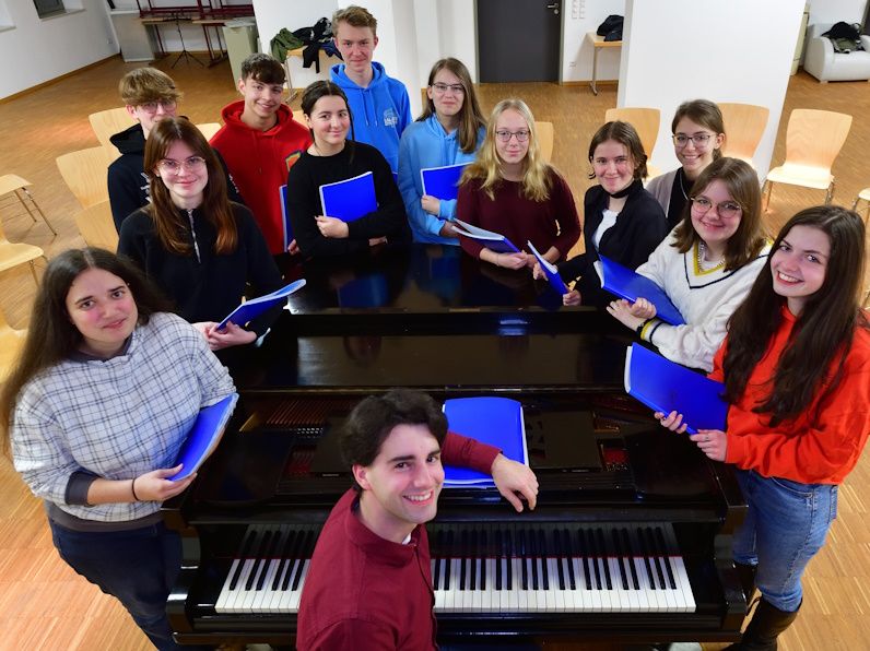 Jugendchor Augustusburg zusammen mit Kirchenmusiker Pascal Kaufmann an einem Klavierflügel.