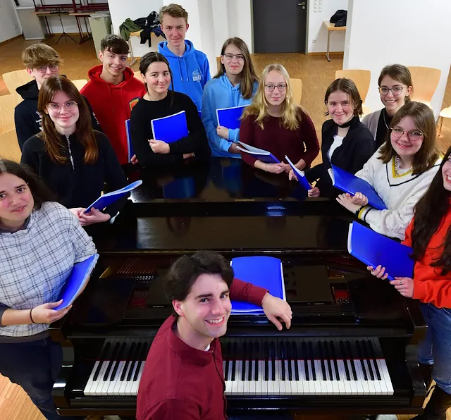 Jugendchor Augustusburg zusammen mit Kirchenmusiker Pascal Kaufmann an einem Klavierflügel.