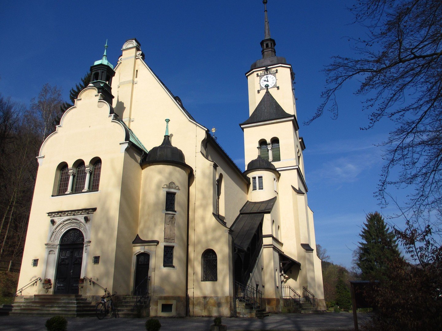 Saalkirche Hohenfichte mit hellbeigen Mauern aus der Froschperspektive vor blauem Himmel.