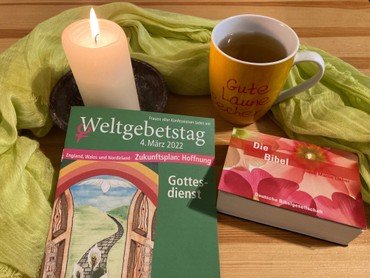 ein Tisch mit einer Broschüre zum Weltgebetstag, einer Kerze und einer Tasse