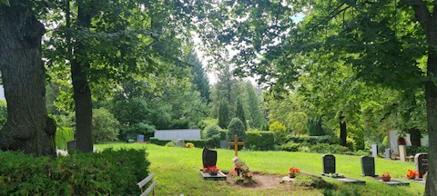Grabstätten unter grünen Bäumen auf dem Augustusburger Friedhof.