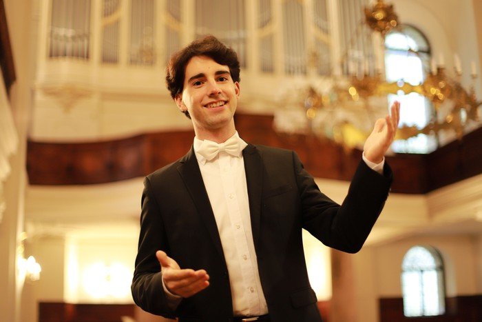 Lächelnder Kirchenmusiker Pascal Kaufmann mit erklärender Geste in der Stadtkirche St. Petri.
