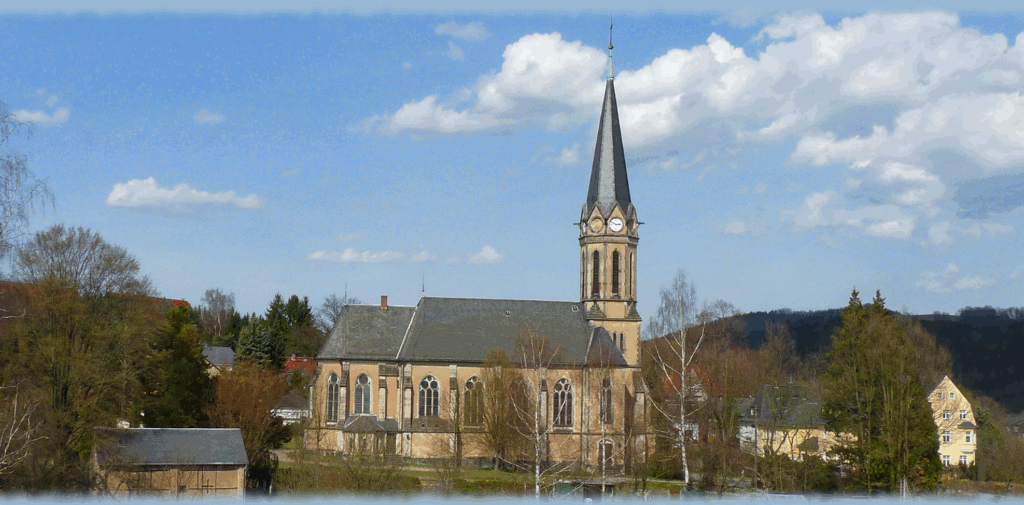 Seitenansicht der Erdmannsdorfer Trinitatiskirche mit beigefarbenen Mauern vor Himmel mit Wolken.