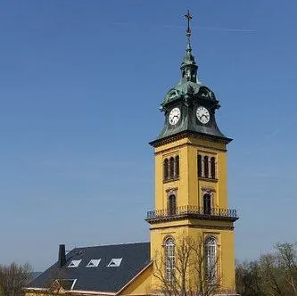 Stadtkirche St. Petri mit gelber Fassade vor blauem Himmel, fotografiert von der Seite.