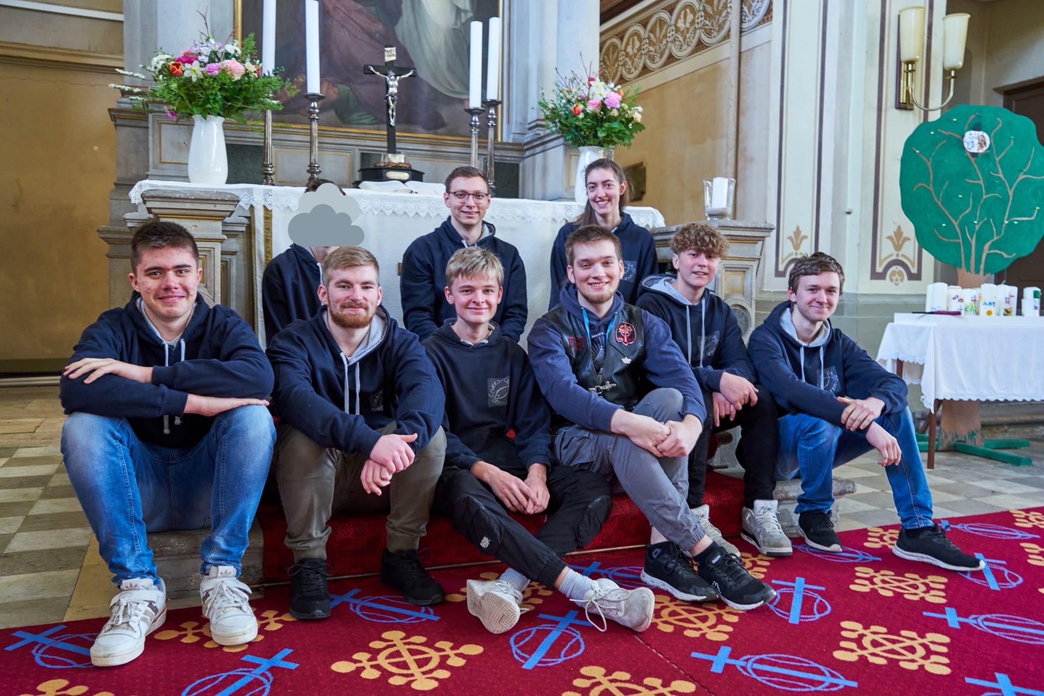 Mitglieder der Jungen Gemeinde sitzen vor dem Altar und freuen sich