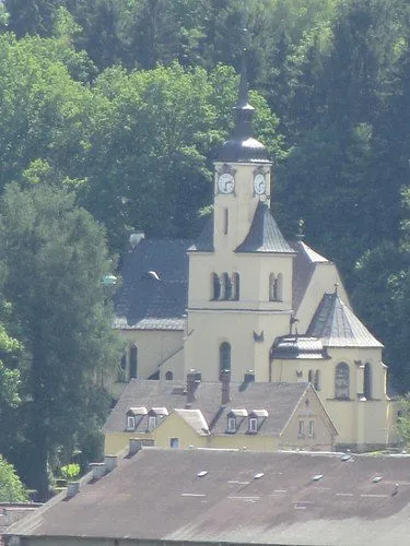 Kirche Hohenfichte hinter einigen Häusern, fotografiert aus größerer Entfernung bei sonnigem Wetter.