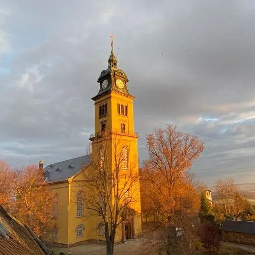 Stadtkirche St. Petri mit gelber Fassade bei Sonnenschein und grauem Himmel im Herbst.
