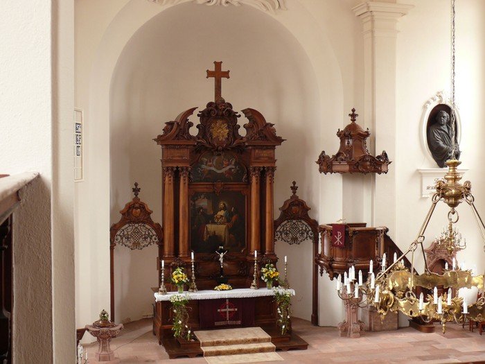 Dunkler, geschmückter Holzaltar der Stadtkiche St. Petri mit Kanzel und Kronleuchter.