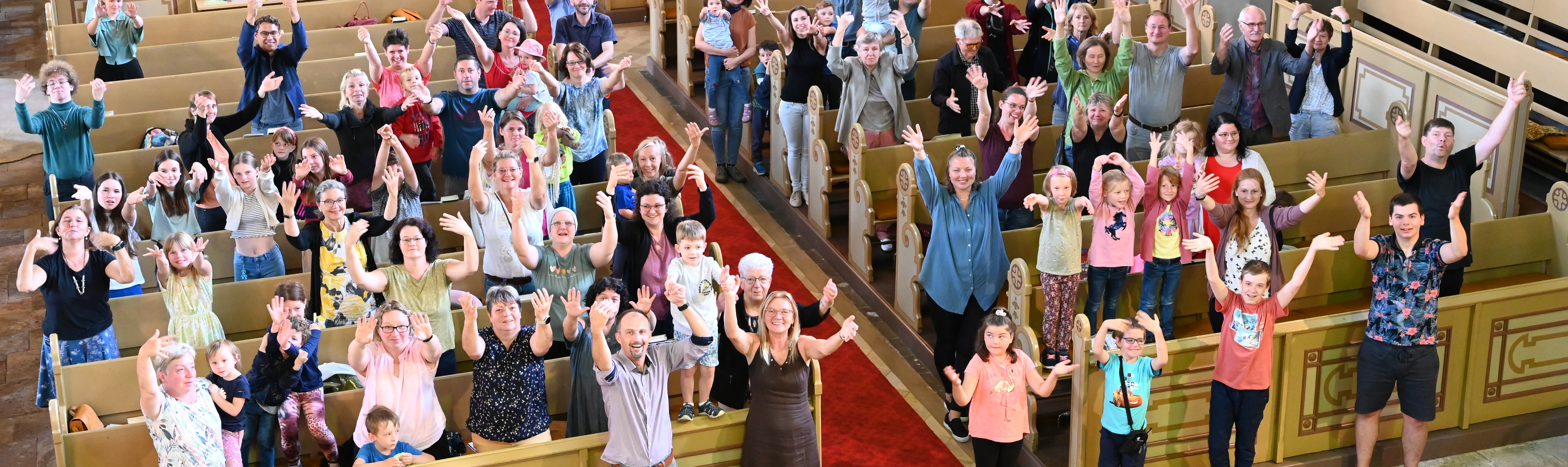 Mitglieder der Kirchgemeinde strecken in der Kirche ihr Arme nach oben