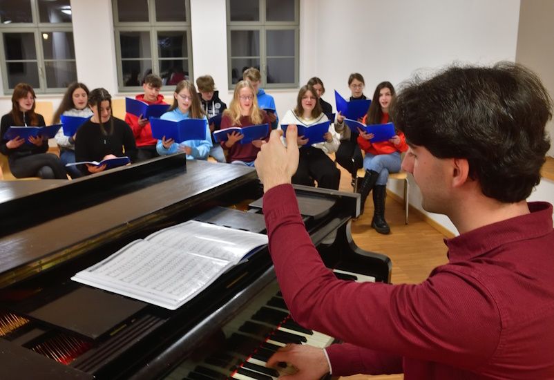 Kirchenmusiker Pascal Kaufmann beim Einstimmen der Jugendchor-Mitglieder am Klavierflügel.