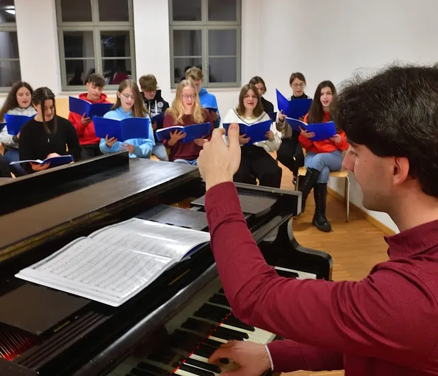 Kirchenmusiker Pascal Kaufmann beim Einstimmen der Jugendchor-Mitglieder am Klavierflügel.