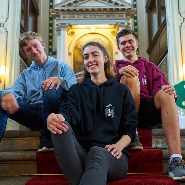 Mitglieder der Jungen Gemeinde sitzen vor dem Altar und freuen sich