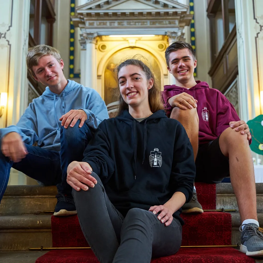 Mitglieder der Jungen Gemeinde sitzen vor dem Altar und freuen sich