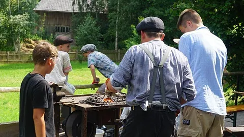 Symbolbild Erlebnistage - Kinder stehen um ein Schmiedefeuer