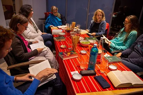 Frauen sitzen um einen gedeckten Tisch und unterhalten sich